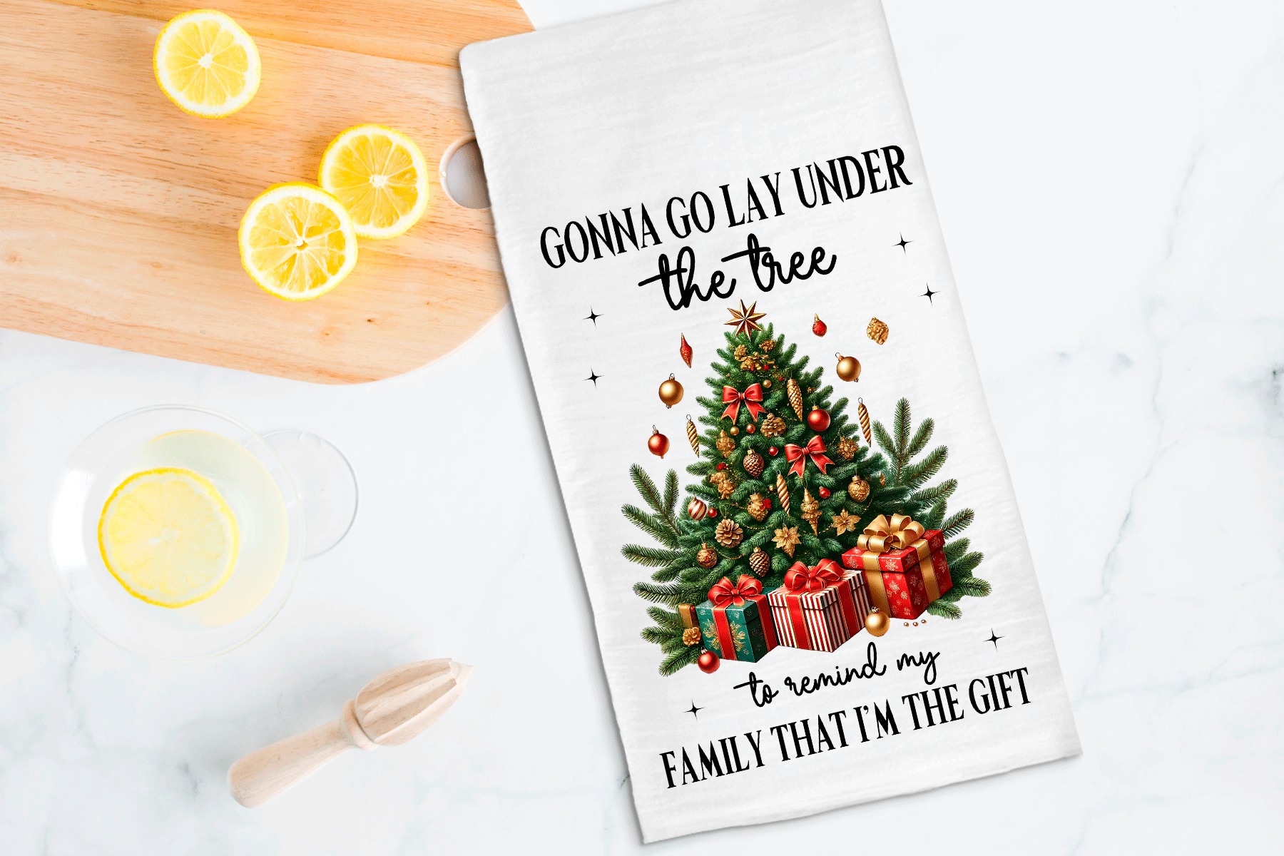 Tea towel with Christmas tree design and humorous text on a kitchen counter with lemons.