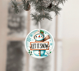 Christmas ornament with snowman holding 'Let It Snow' sign, hanging on a tree.