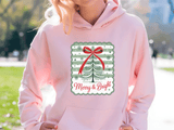 Person wearing a pink hoodie with a Christmas-themed design outdoors.