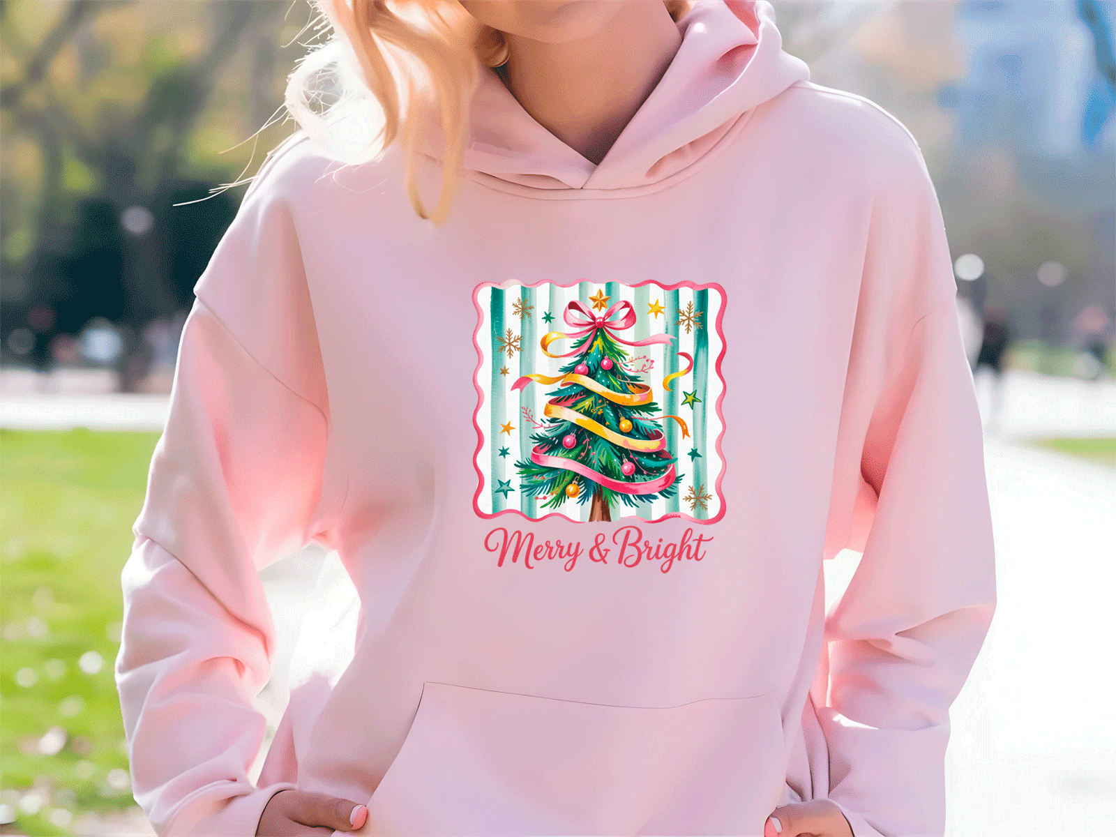 Person wearing a pink hoodie with a Christmas tree design and 'Merry & Bright' text.