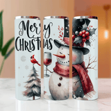 Three Christmas-themed tumblers with snowman, cardinal, and wine glass designs on a blurred indoor background.
