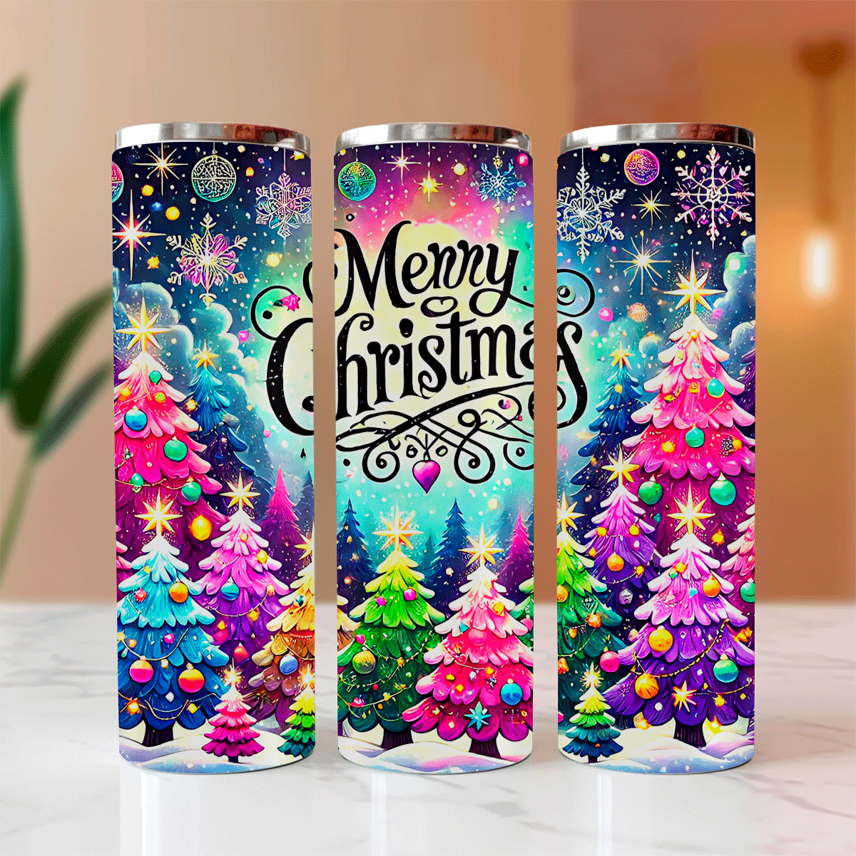 Three colorful tumblers with Christmas tree designs and 'Merry Christmas' text on a blurred background.