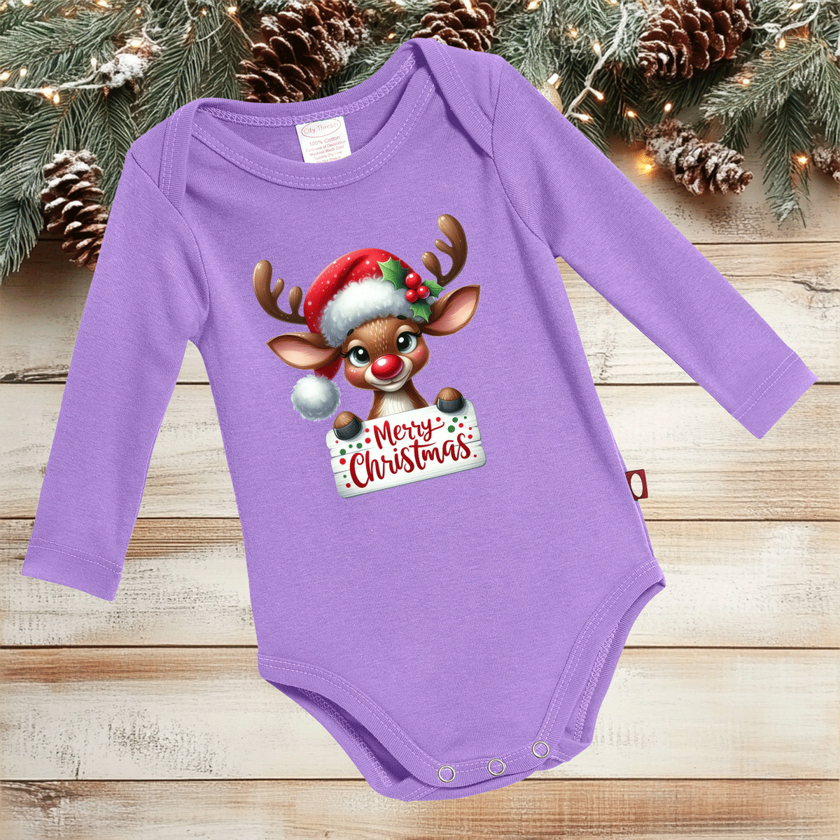 Purple baby onesie with a Christmas reindeer design on a wooden surface with holiday decorations.