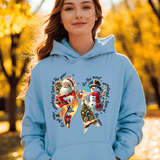 Woman wearing a light blue hoodie with Christmas-themed designs and text, standing in an autumn setting.