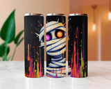 Three tumblers with a mummy design and colorful splashes on a marble surface.