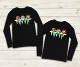 Two black long-sleeve shirts with Christmas-themed graphic on a wooden surface
