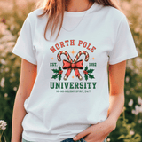Person wearing a white t-shirt with 'North Pole University' design featuring candy canes and a bow.