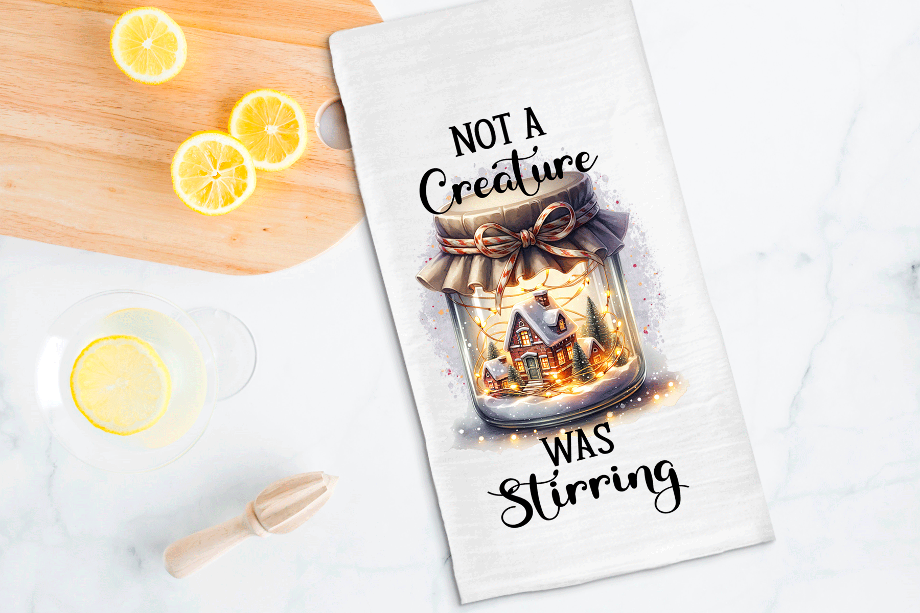 Tea towel with a jar of lights design and text on a kitchen counter with lemons.