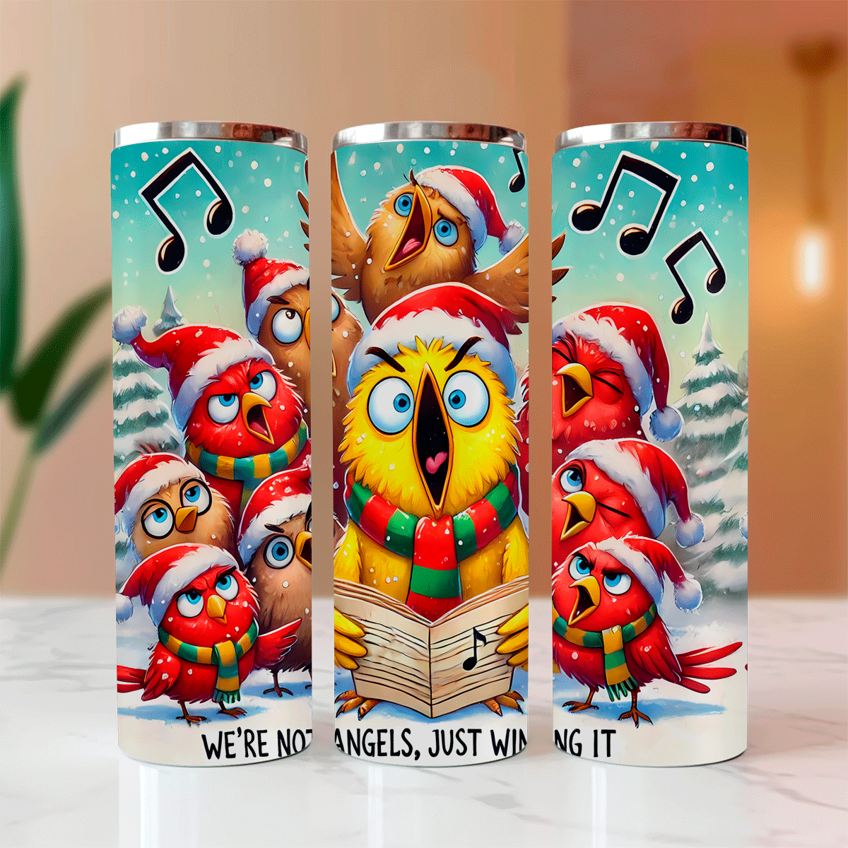 Three colorful tumblers with cartoon birds in Christmas hats and scarves on a light surface.