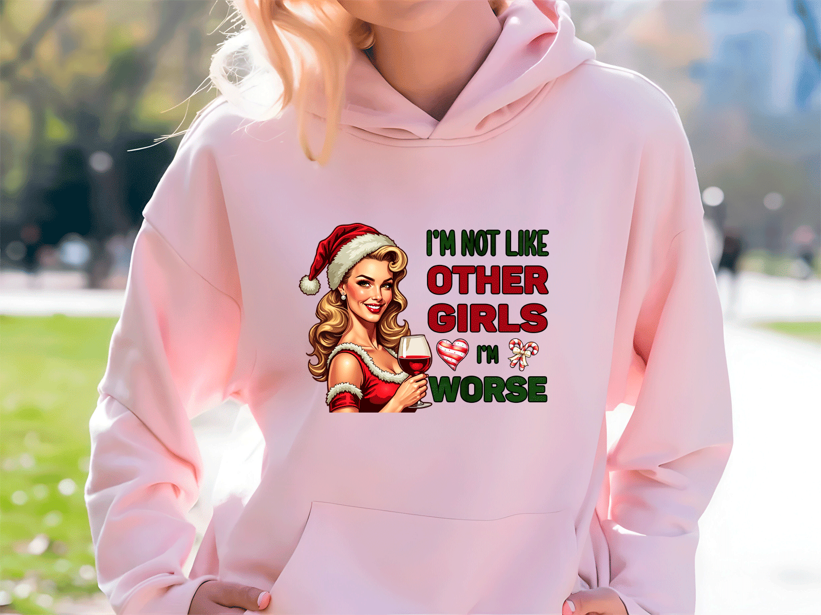 Person wearing a pink hoodie with a graphic design and text outdoors.