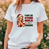 White t-shirt with a graphic of a woman in a Santa hat holding a glass of wine, text 'I'm not like other girls, I'm worse', and blurred natural background.
