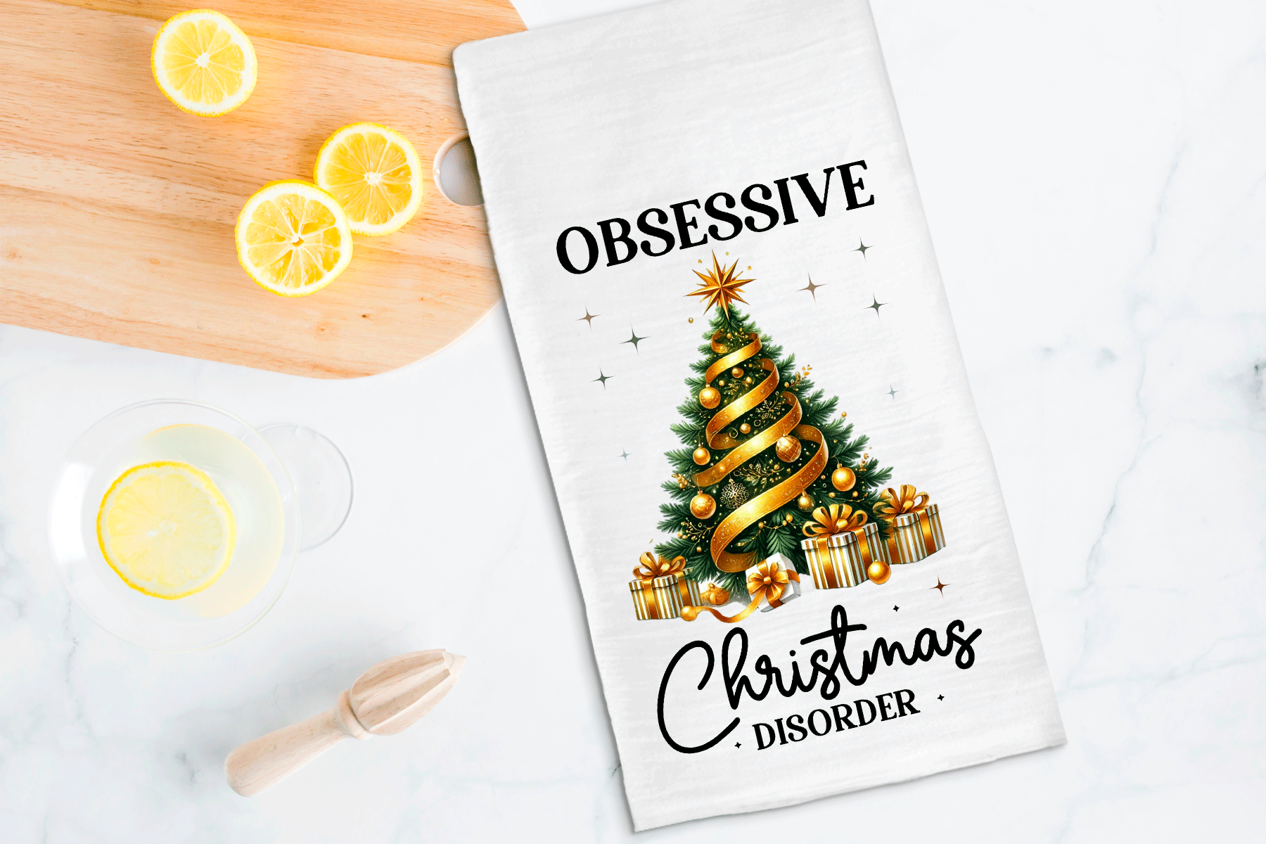 Tea towel with Christmas tree design and text on a kitchen counter with lemons.