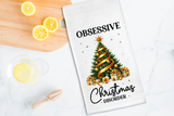 Tea towel with Christmas tree design and text on a kitchen counter with lemons.