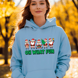 Person wearing a light blue hoodie with Christmas-themed design and text, standing in an outdoor setting with trees.