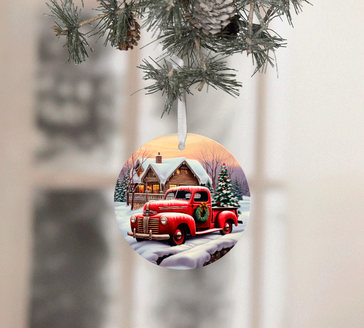 Christmas ornament with a red truck and cabin design, hanging from a tree.