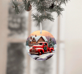Christmas ornament with a red truck and cabin design, hanging from a tree.