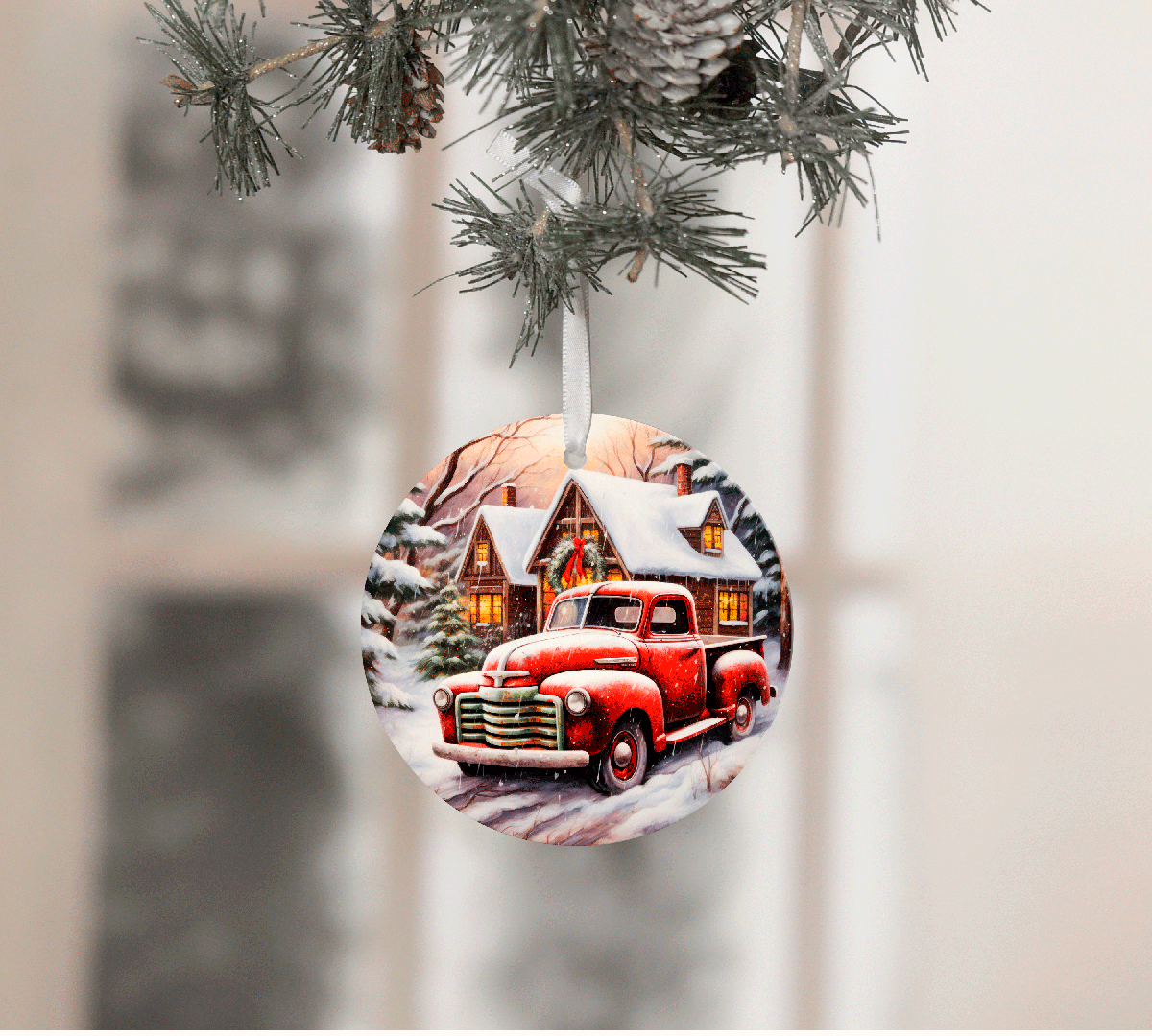 Christmas ornament with a red truck and snowy cabin design, hanging from a tree.
