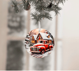 Christmas ornament with a red truck and snowy cabin design, hanging from a tree.