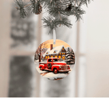 Christmas ornament with a red truck and snowy village scene, hanging from tree branches.