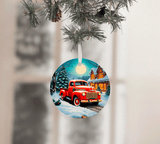 Christmas ornament with a red truck design hanging on a tree branch.