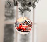 Decorative Christmas ornament with a red truck and cabin design, hanging from a tree.