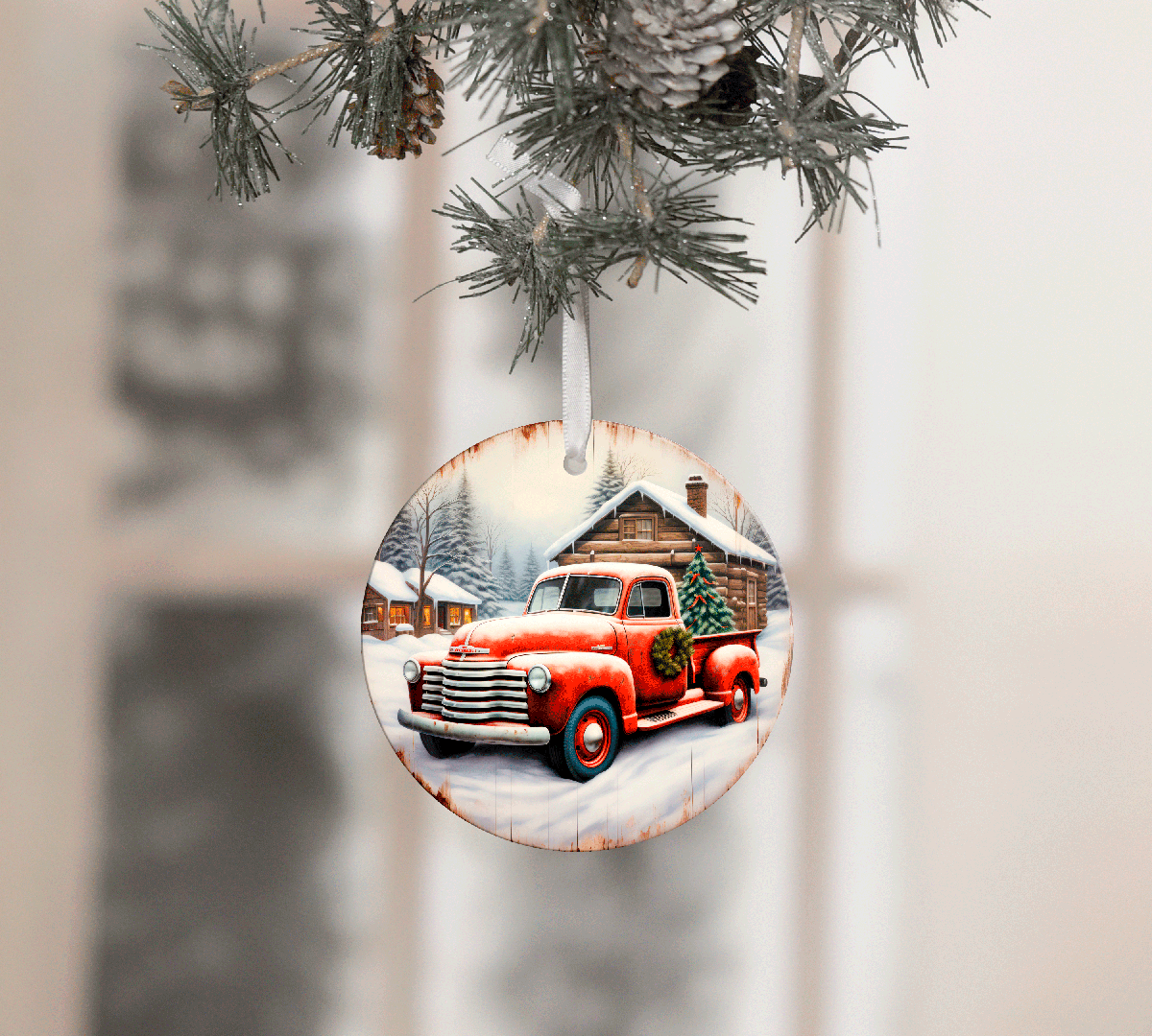 Christmas ornament with a red truck and cabin design, hanging on a tree.