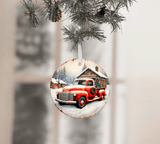 Christmas ornament with a red truck and cabin design, hanging on a tree.