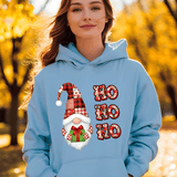 Person wearing a light blue hoodie with a Christmas-themed design featuring a gnome and 'HO HO HO' text, standing in an autumn setting.