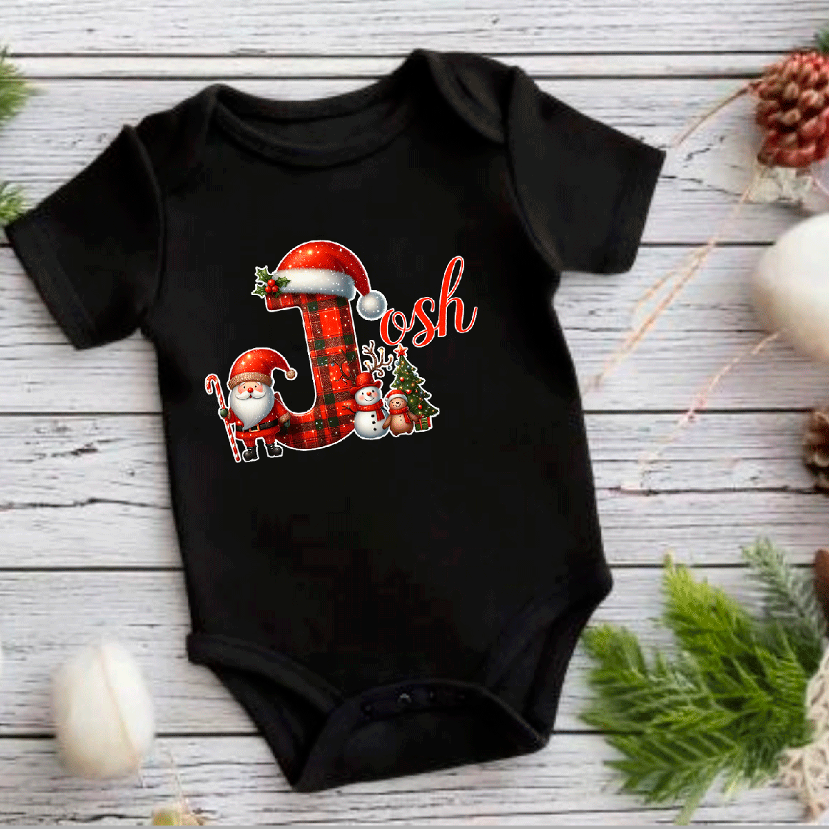 Black baby onesie with Christmas-themed design on a wooden surface.