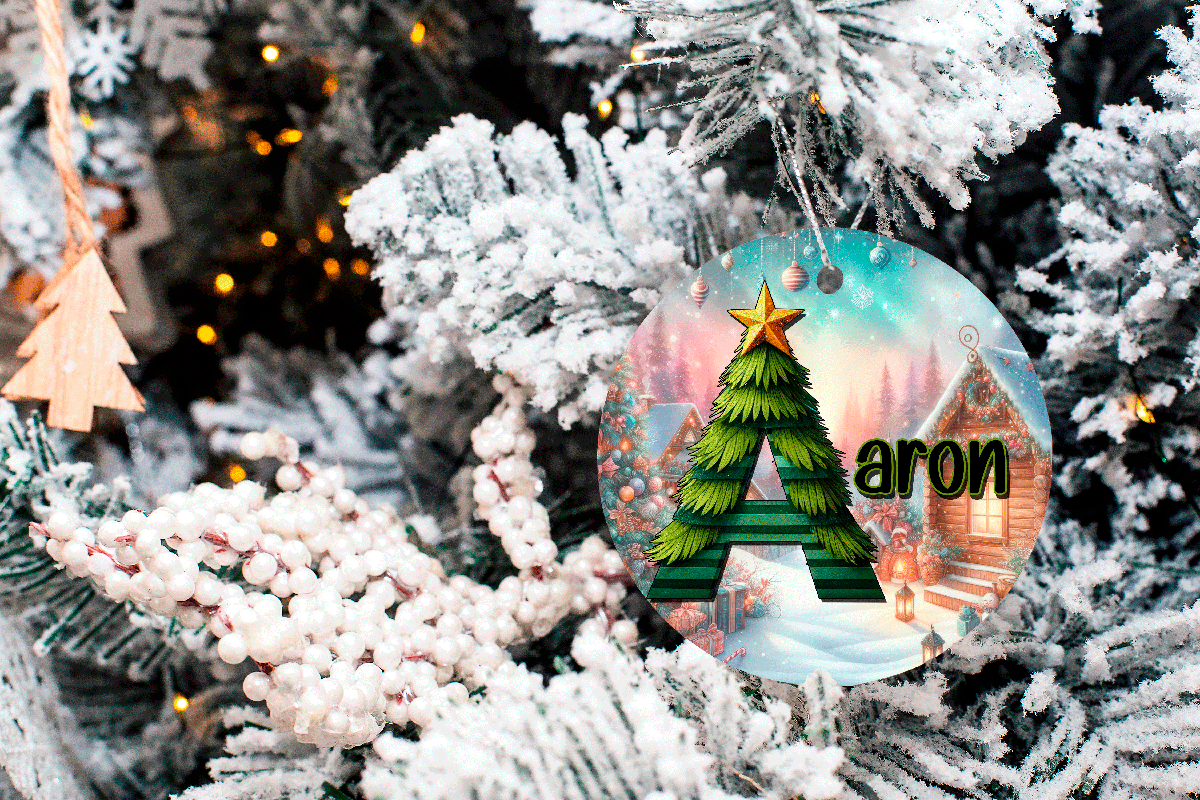 Decorative Christmas ornament with a tree design and 'aron' text, hanging on a frosted Christmas tree.