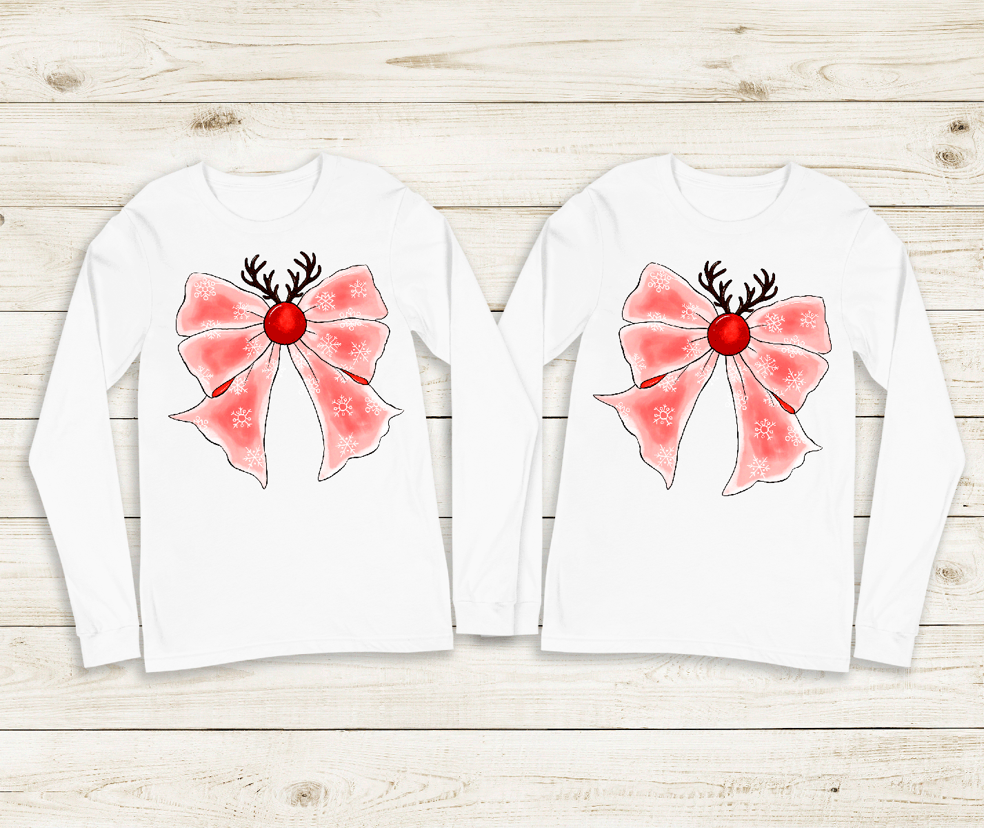 Two white long-sleeve shirts with pink bows and reindeer antlers on a wooden surface.