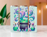 Three tumbler with a colorful design of potions and a cauldron on a marble surface.