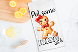 Tea towel with a gingerbread man design and text 'Put some icing on it' on a kitchen counter with lemons.