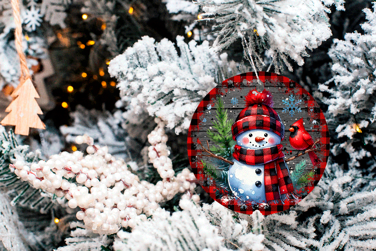 Decorative Christmas ornament with a snowman and plaid pattern on a tree.