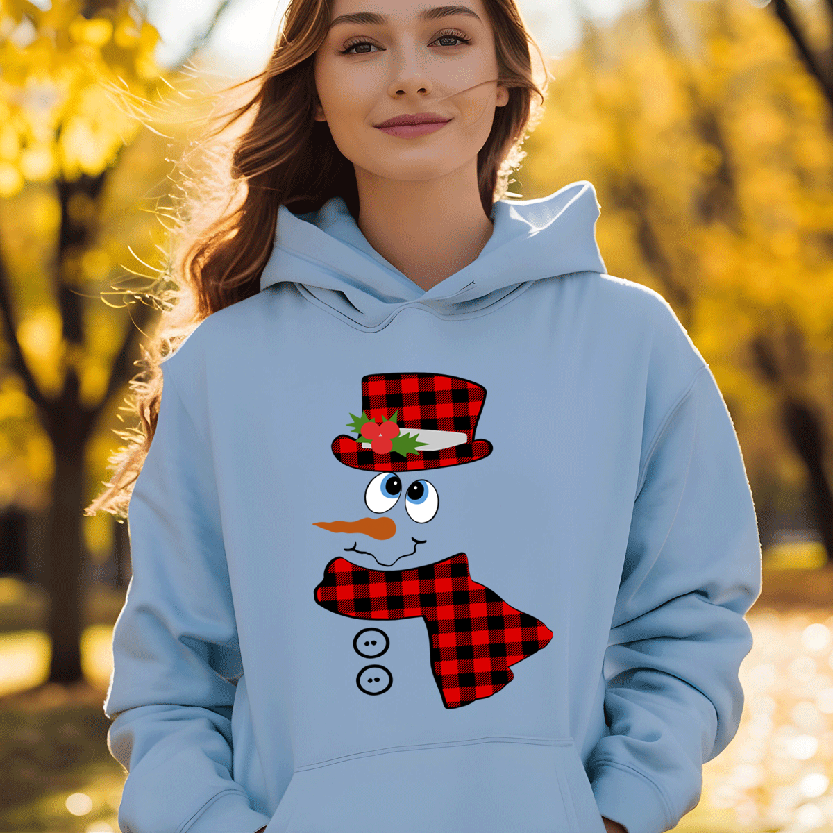Person wearing a light blue hoodie with a snowman design in an autumn setting