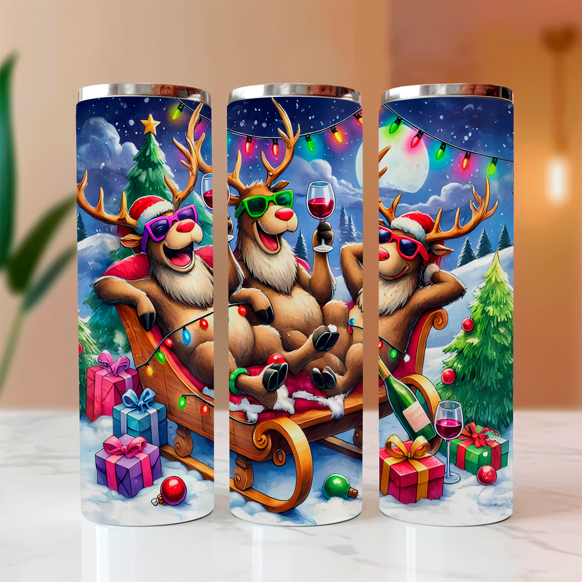 Three festive tumblers with cartoon reindeer characters on a snowy landscape.