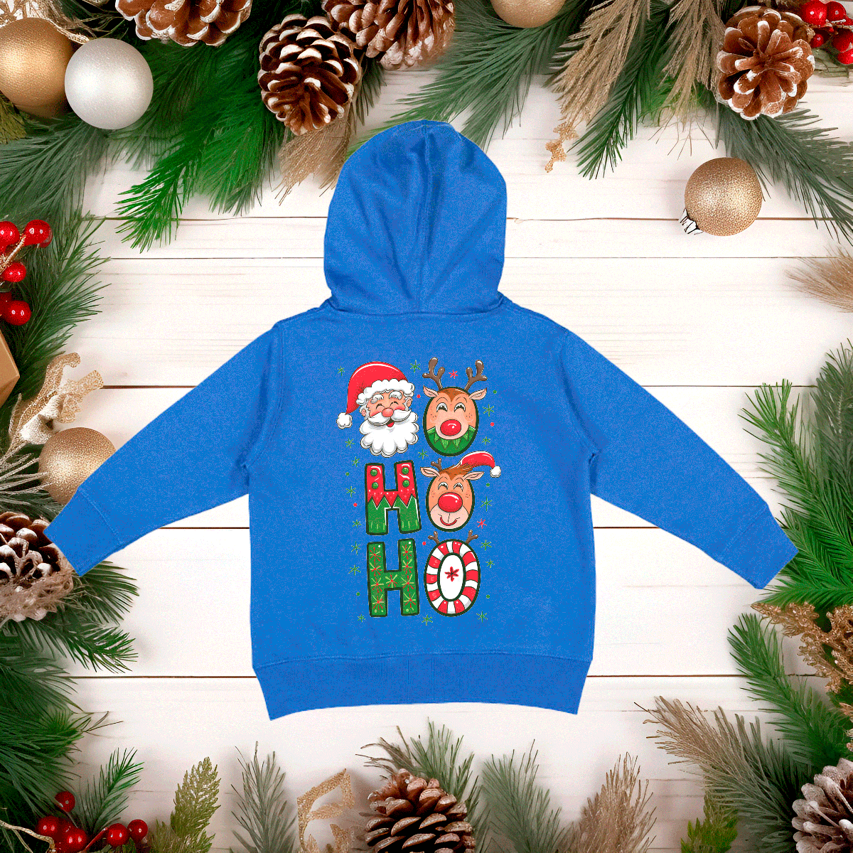 Blue hoodie with Christmas-themed design on a wooden surface with festive decorations.