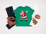Green t-shirt with a Santa Claus graphic, paired with jeans, boots, and a hat on a light gray background.