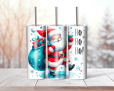 Three Christmas-themed tumblers with Santa Claus and gift designs on a wooden surface.