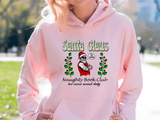 Person wearing a pink hoodie with 'Santa Claus Naughty Book Club' design outdoors.