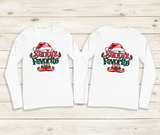 Two white long-sleeve shirts with 'Santa's Favorite' text and elf design on a wooden surface.