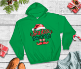 Green hoodie with 'Santa's Favorite' text on a wooden surface with Christmas decorations.