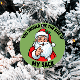 Christmas ornament with Santa Claus pointing and text 'You should see the size of my sack' on a snowy tree background.