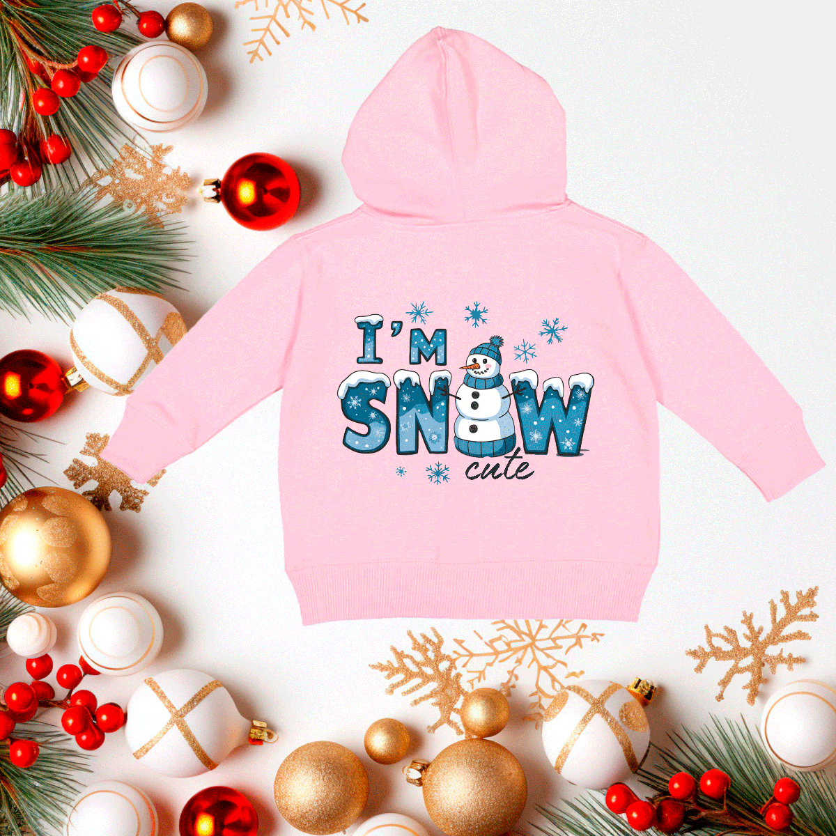 Pink hoodie with 'I'm Snow Cute' text on a festive background with Christmas decorations.