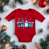 Red baby onesie with 'I'm Snow Cute' text surrounded by Christmas decorations on a white background