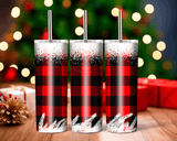Three red and black plaid tumblers with silver straws on a wooden surface with a festive background.