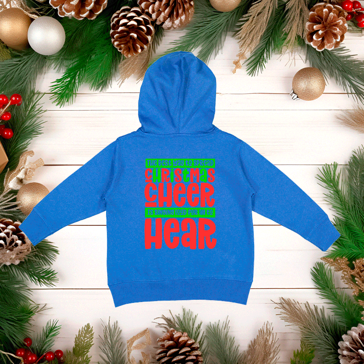 Blue hoodie with colorful text on a wooden surface with Christmas decorations