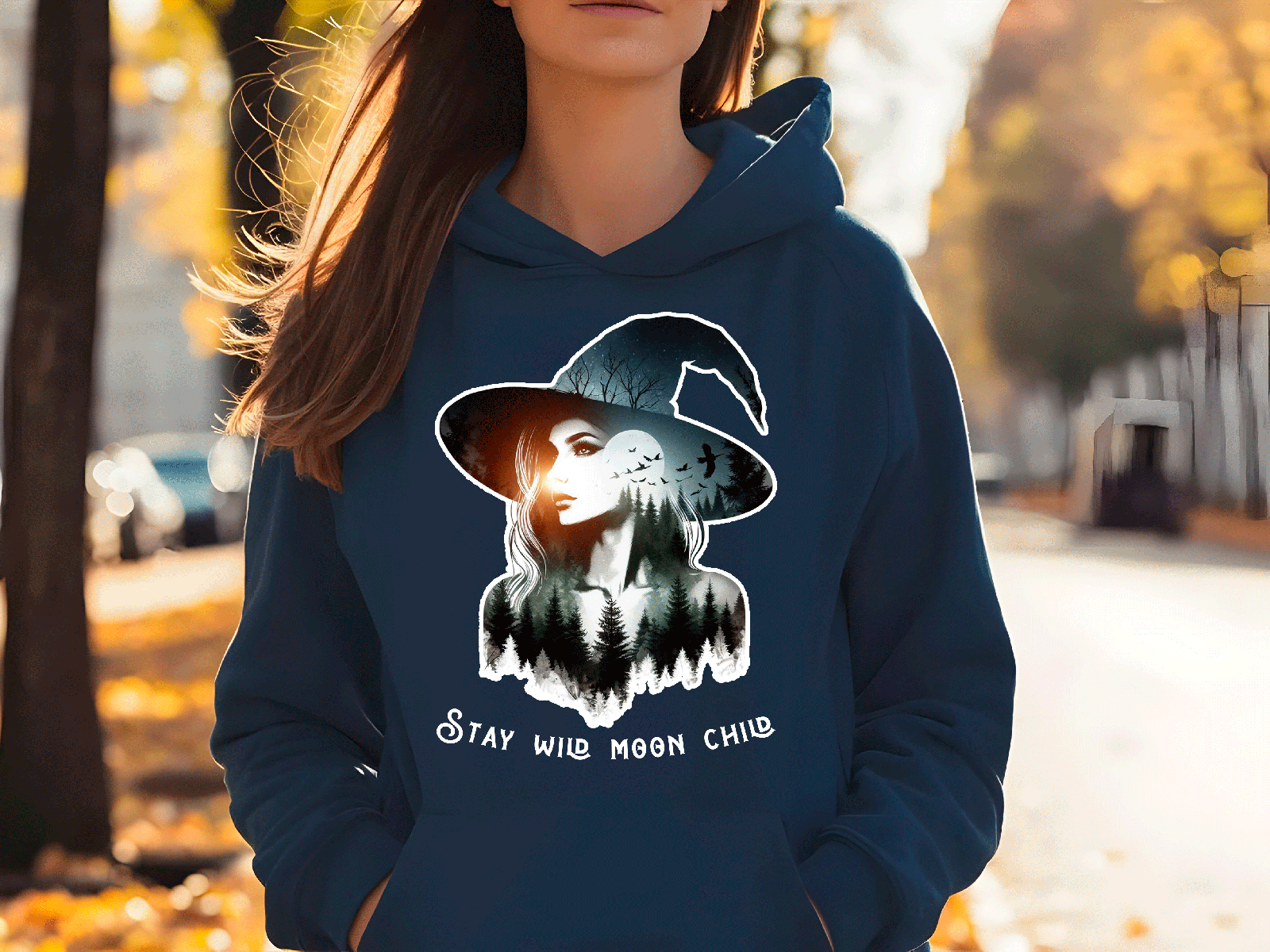 Person wearing a blue hoodie with a witch graphic and text outdoors.