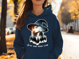 Person wearing a blue hoodie with a witch graphic and text outdoors.