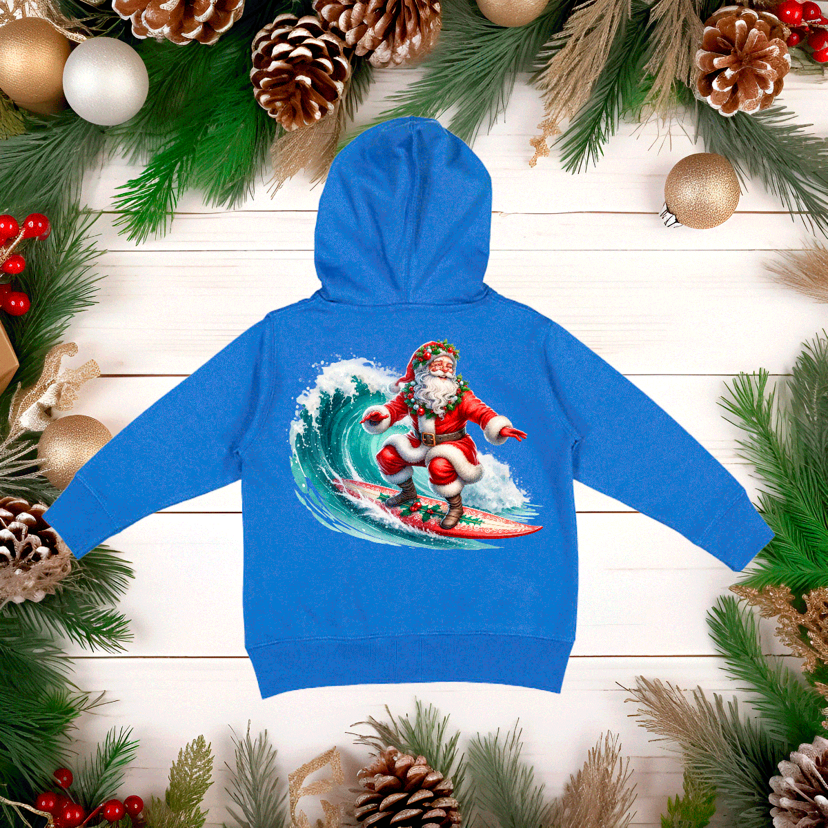 Blue hoodie with a Santa Claus surfing design on a wooden background with Christmas decorations.
